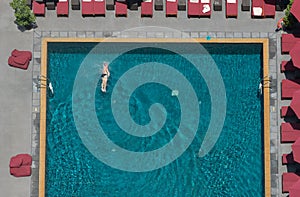 A man swim in the pool at the hotel with red beach umbrella