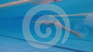 Man swimmer dives underwater in a pool and swims underwater. slow motion pool jumping, swimming technique. Water sports.