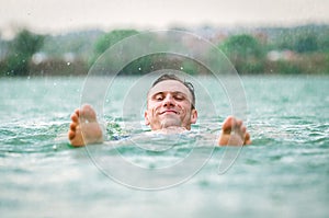 Man swimming in lake under the rain in thunderstorm