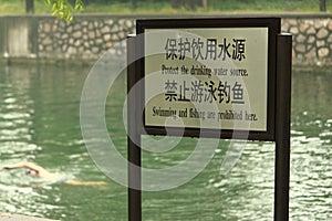 Man is swimming near sign'swimming forbidden'