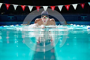 Man, swimming pool and exercise for sport with splash, speed and training for wellness, health and fitness. Swimmer