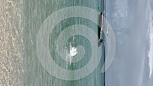 Man swimming towards boat floating on sea against sky