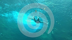 Man swimming under tuquoise blue water of a waterfall stream. Underwater view.