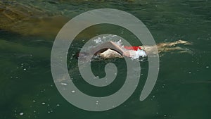 A man swims breaststroke in the river against the current