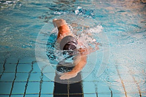 Man swims front crawl style in swimming pool