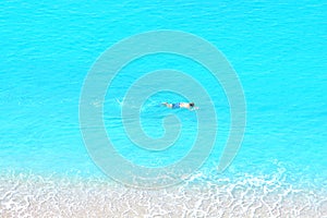 Man swims in the sea with a mask and snorkel. View from mountain.