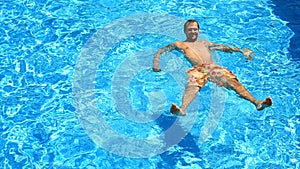 A man swims under the water in a pool with blue water. view from above.