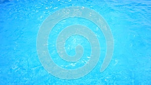 A man swims under the water in a pool with blue water. view from above.