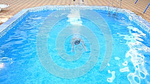 A man swims under the water in a pool with blue water. view from above.