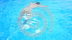 A man swims under the water in a pool with blue water. view from above.