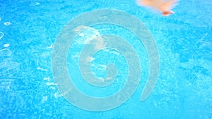 A man swims under the water in a pool with blue water. view from above.