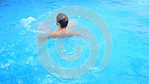 A man swims under the water in a pool with blue water. view from above.