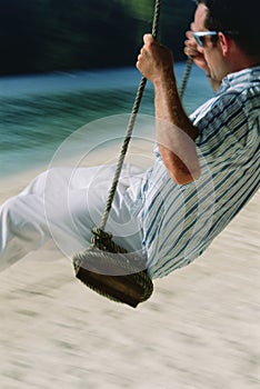 Man on swing at beach