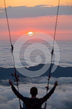 Man on swing enjoying scenic sunset over clouds at Huser highlands