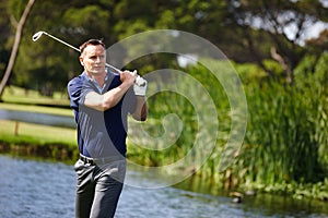 Man, swing and golfer with club by lake for point, score or par shot in outdoor nature. Male person or sports player