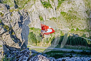 Man swinging in a hammock set up high in the air, between two mountain ridges