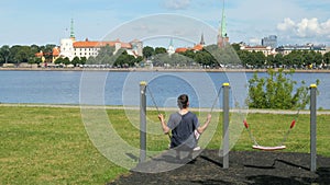 man swinging on swing, watching riga view, latvia