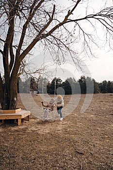 A man swings a girl on a swing in a field.