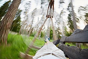 Man swings on wooden swing, legs and blurred