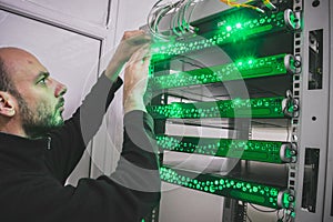 A man switches the wires in the computer equipment. The technician supports the work of a modern datacenter. Technological concept
