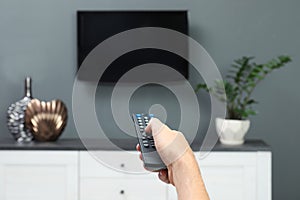 Man switching channels on plasma TV with remote control