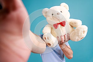 Man in T-shirt broadcasting livestream, point of view photo, hiding his face behind soft teddy bear