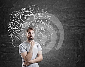 Man in T-shirt and business plan sketches on blackboard