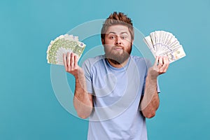 Man in T-shirt holding fans of dollar and euro banknotes, currency exchange rates, payment service.