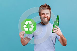 Man in T-shirt holding glass bottle and recycling green symbol, sorting his rubbish, saving ecology.