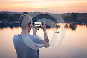 Man with tab makes photo of the sunset