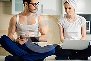 Man with tablet his girlfriend`s using laptop and spying each other