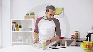 Man with tablet pc eating breakfast at home