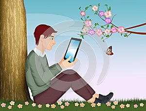 Man with tablet sitting in the grass photo