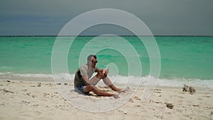 Man with a tablet on a tropical beach.