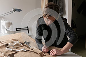 Man tailor making clothing pattern while work in workshop