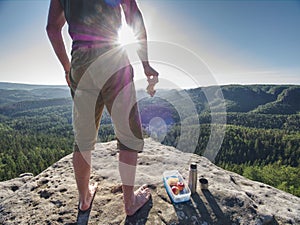 Man take brak for snack while climbing in rocks. Hiker in shorts