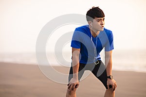 Man take break after running on  beach at sunset