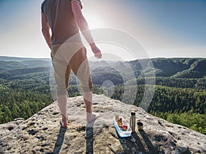 Man take break for snack while climbing in rocks. Hiker in shorts