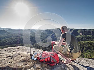 Man take break for snack while climbing in rocks. Hiker in shorts