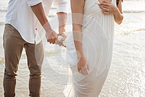 Man take care his girlfriend on beach. Boyfriend wring out the water white dress. Romantic couple on the beach