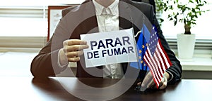 Man take a flag with text PARAR DE FUMAR with flags on the office background photo