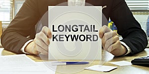 Man take a paper with text Longtail Keyword on the shirt with office background