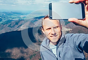 Man take self photo with smartphone on the top of mountain