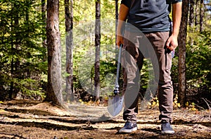 A man take a shovel in dark forest