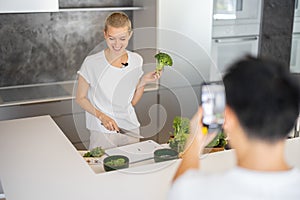 Man take video on smartphone of woman cook salad