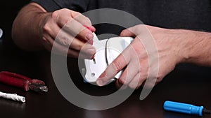 A man takes apart an iron with a screwdriver. Repairing a burnt iron at home. Tools for repair are on the table nearby. Close-up