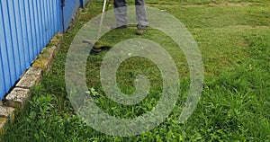 A man takes care of the grass on his front lawn with an environmentally friendly electric lawnmower. A man on his lawn