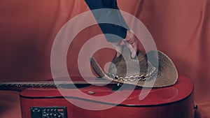 Man takes a cowboy hat with red, acoustic guitar photo