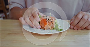 Man takes delicious sandwich with salmon and fresh herbs from plate lunch to recharge energy. Nutritious lunch will give