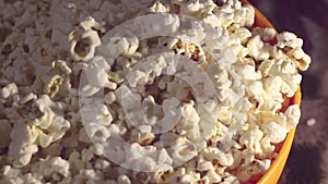 A man takes fresh hot popcorn from a bowl. A male hand picks popcorn from a bucket.